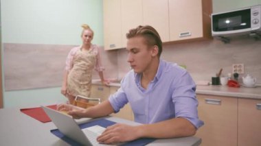 Bir adam bilgisayarın başında otururken portakal suyu içer.